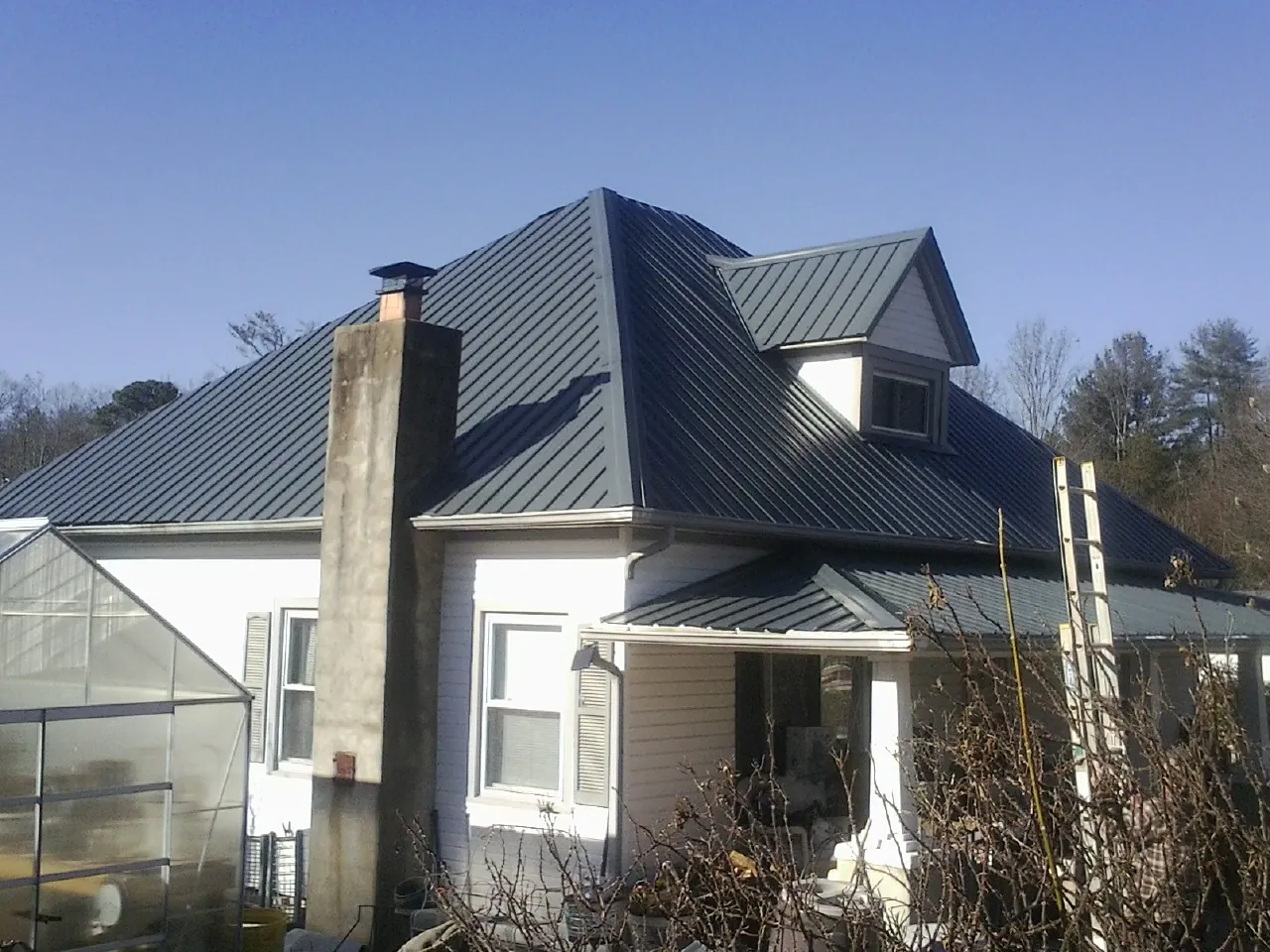 Dark blue standing seam metal roof on a white farmhouse with dormer — Slate & Tile Roof Repair by Roofing Brothers in Hallam