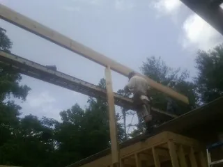 Carpenter setting a ridge beam over a new addition frame — Ice Dam Removal by Roofing Brothers in Hallam