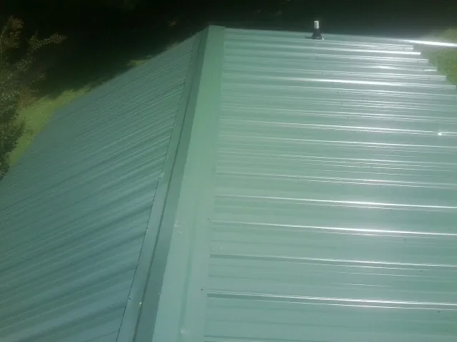 New green metal panels meeting at the ridge of a roof — Flat Roof Repair work by our crew in Hallam