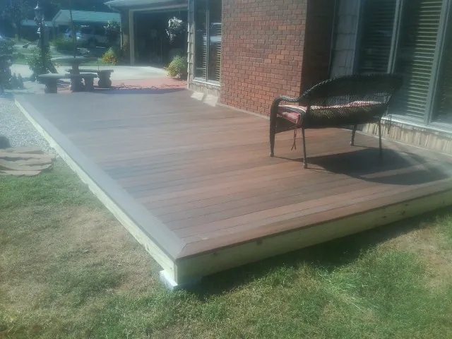 New wood deck and wicker chair beside a brick house in Hallam