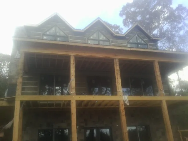 Dormers and porch framing on a large log home under construction — Roof Coating work by our crew in Hallam