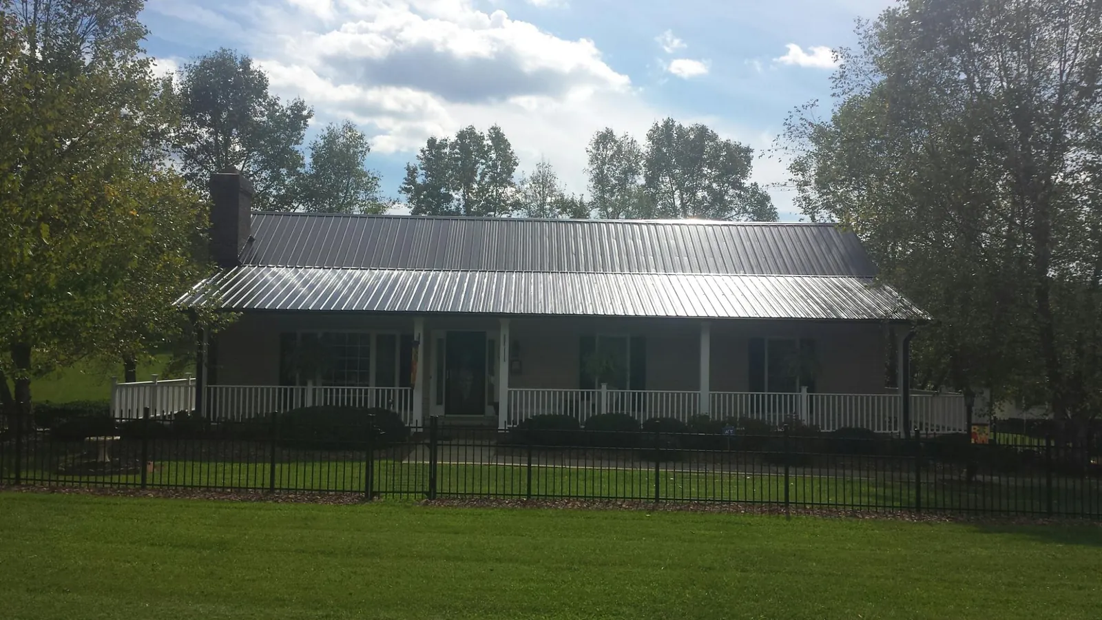 Gray metal roof on a brick ranch with a full width front porch — Gutter Guard Installation work by our crew in Hallam