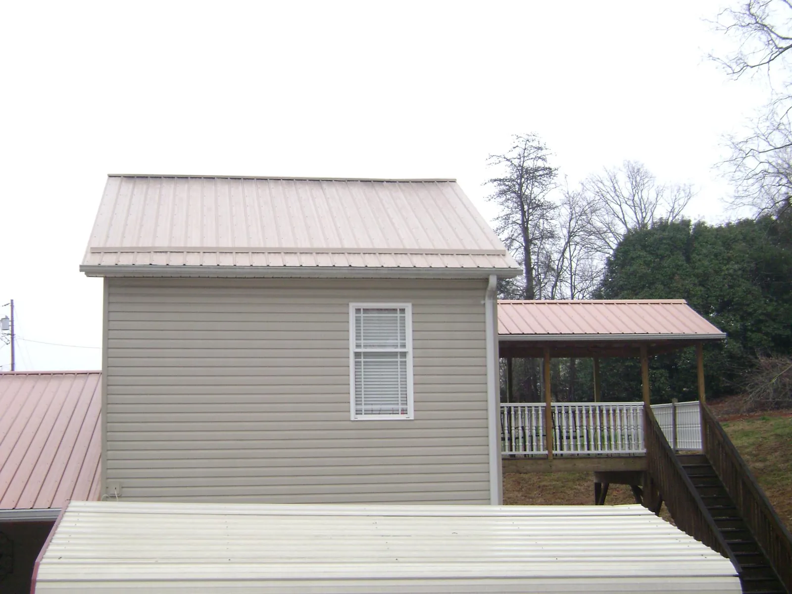 Tan metal roofs on a two story addition and attached porch, from a Roof Replacement job in Hallam